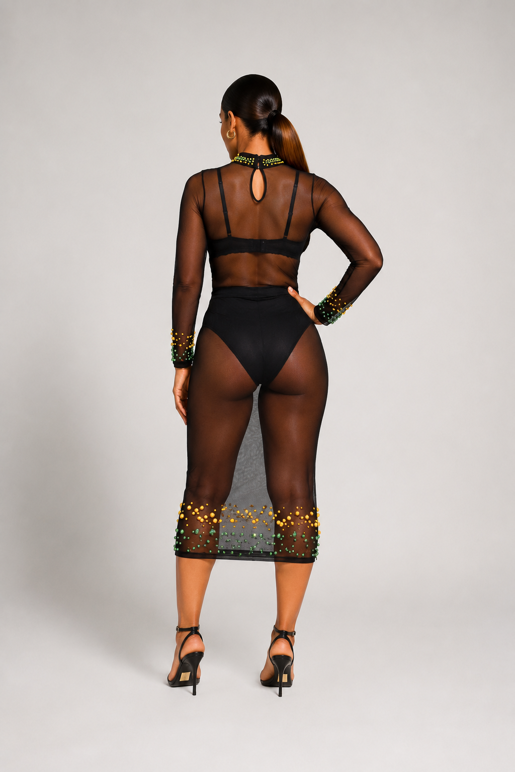 Back view of a luxury black sheer mesh dress featuring hand-beaded green and gold detailing, keyhole neckline, and fitted midi silhouette.